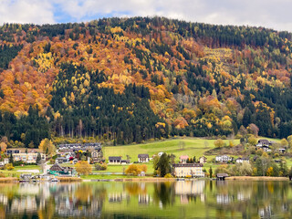 Austria's Carinthian lake Ossiacher See in autumn with a view of ducks and a village on the shore