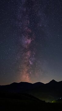 Vertical view of milky way galaxy stars moving over mountains rural landscape Astronomy time lapse