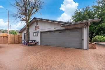 A white house with a gray garage and picnic table in front