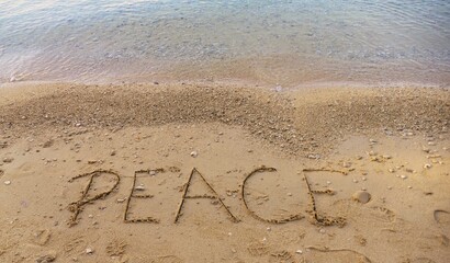 Sandy beach by the sea with letters written in the sand - PEACE