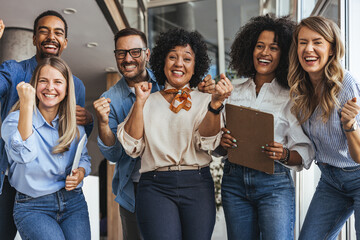 Diverse Team Celebrating Success In Office Corridor With Clipboards And Big Smiles
