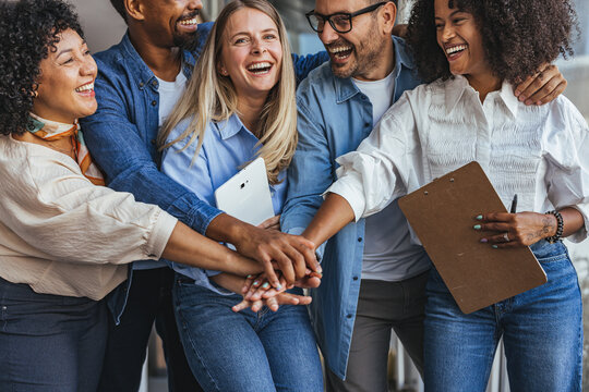 Diverse Team of Friends Celebrates Together with Hands Joined, Smiling in Casual Office Collaboration Today