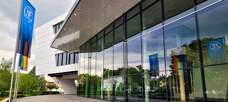 Friedrichshafen, Germany - May 8, 2024. The modern ZF Forum building, the global headquarters of technology company ZF Friedrichshafen AG. ZF Company and LGBT flags flutter nearby.