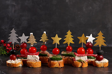 An assortment of various Canapes with tomatoes, pate, mozzarella cheese, salami, herring, olives, and grapes on a marble table. Christmas and New Year's dishes, a set of appetizers for festive table