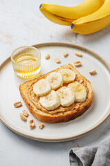 Peanut butter sandwich and banana on a plate on a marble background