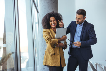 Happy Business Partners Laughing Together in Modern Office Corridor with Tablet