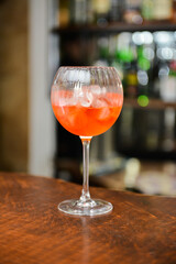 Closeup glass of spritz aperol cocktail decorated with orange at bright bar counter background.