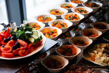 Fototapeta premium A variety of fresh dishes displayed on a buffet table at a catered event, featuring salads, appetizers, and hot meals arranged in a professional food service setup