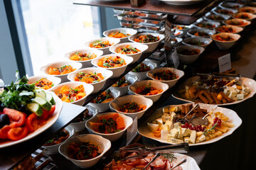 A variety of fresh dishes displayed on a buffet table at a catered event, featuring salads, appetizers, and hot meals arranged in a professional food service setup