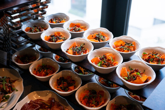 A variety of fresh dishes displayed on a buffet table at a catered event, featuring salads, appetizers, and hot meals arranged in a professional food service setup
