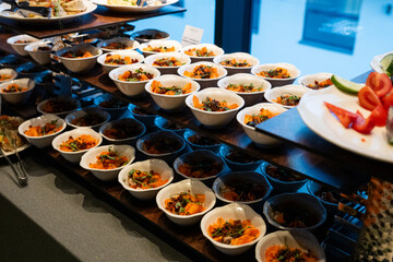A variety of fresh dishes displayed on a buffet table at a catered event, featuring salads, appetizers, and hot meals arranged in a professional food service setup