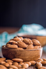 Almond kernel nuts in bowl on wooden table.