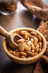 Almond kernel nuts in bowl on wooden table.