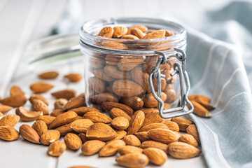 Almond kernel nuts in jar on white table.