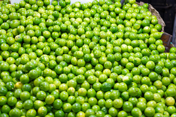 A large pile of fresh, vibrant green limes at a market.