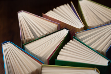 Hardcover books, colored covers textbooks, top view, on wooden surface. Books and reading are necessary for self-improvement, gaining knowledge and success in career, business and personal life.