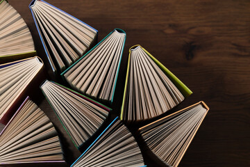 Hardcover books, colored covers textbooks, top view, on wooden surface. Books and reading are necessary for self-improvement, gaining knowledge and success in career, business and personal life.