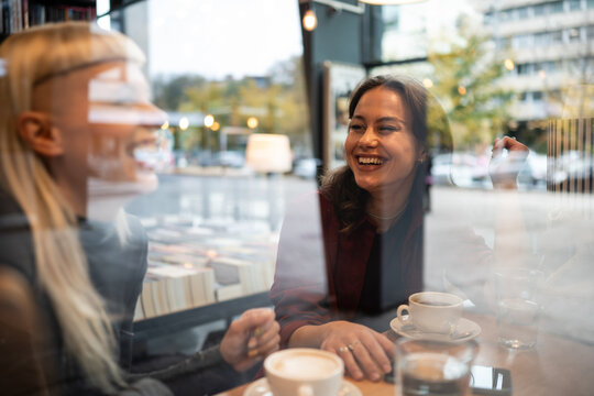 Women friends laughing and enjoying coffee in cafe