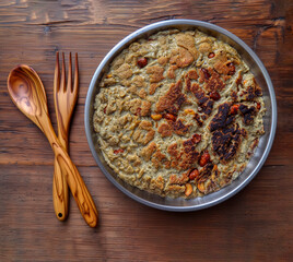 View of a gachamiga on a metal plate on a wooden table with a wooden fork and spoon as well, Elda, Alicante, Spain, Europe