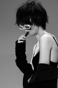 Black and white portrait of a stylish woman wearing sunglasses with thoughtful expression and edgy hairstyle