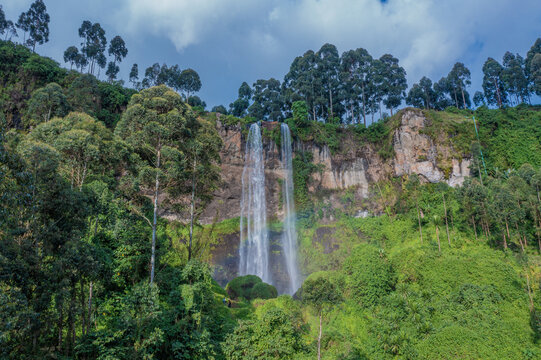 Aerial view of the cascading Sipi Falls as it plunges down the cliffside amidst lush green vegetation, Sipi Falls, Eastern Region, Uganda.