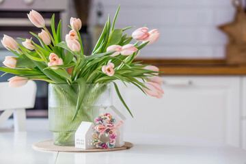 A bouquet of spring tulips on a white table in a white kitchen interior. The concept of home comfort, International Women's Day on March 8.