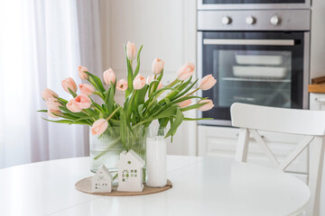 The concept is timed to the arrival of spring and International Women's Day on March 8. A bouquet of spring, delicate, pink tulips in a beautiful stylish vase on the table.