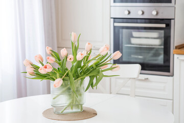 The concept is timed to the arrival of spring and International Women's Day on March 8. A bouquet of spring, delicate, pink tulips in a beautiful stylish vase on the table.