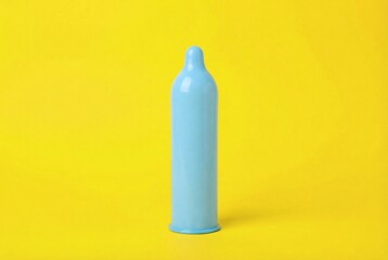 Blue condom symbolizing protection and awareness on a vibrant yellow background, representing World AIDS Day initiatives.