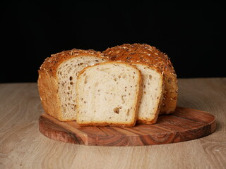 Two loaves of whole-grain bread on wooden cutting boards. One loaf is sliced, with two slices visible in the foreground.