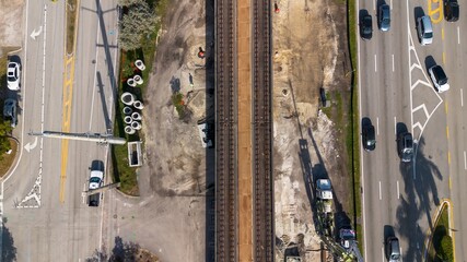 Aerial view of road construction repair site with working cranes next to moving railway system on a sunny day