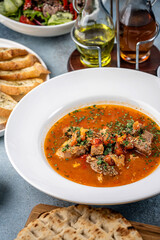 hearty meat and vegetable soup in white bowl