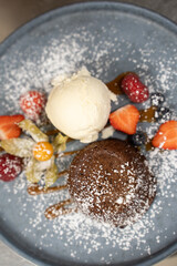 Chocolate fondant with ice cream and berries on plate.
