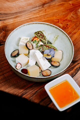 Unique dessert presentation with cheese, fruits, and sauce on wooden table
