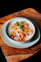 Delicious bowl of yogurt topped with fruit and nuts served on a wooden board