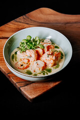 Shrimp in creamy sauce served in a stylish bowl on a wooden board