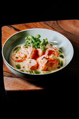 Fresh shrimp served in creamy sauce with herbs on wooden board