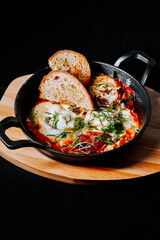 Delicious baked eggs with fresh herbs and crusty bread served in a skillet