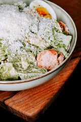 Freshly made salad with chicken and cheese served on a wooden board