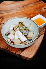 Creative food presentation with cheese, fruits, and edible flowers on a wooden board