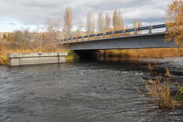A backroad bridge spans a river on a fall day.