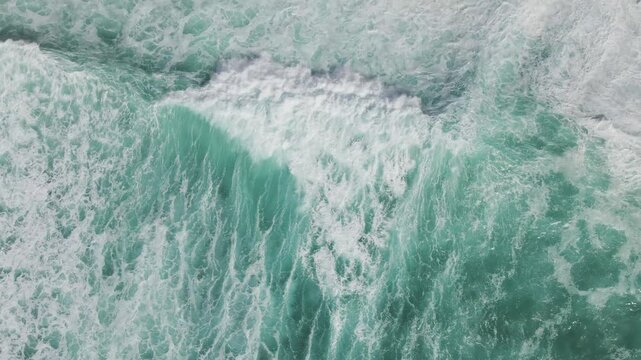 Aerial view of the contrasting turquoise ocean meeting the sandy shore, a dynamic interplay of textures and tones, Costa da Caparica, Setubal, Portugal.