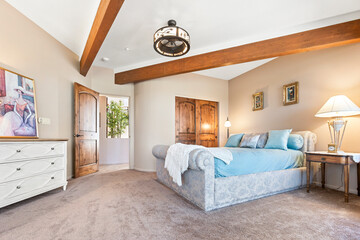 A large bedroom with a king bed, dresser, nightstand, and TV