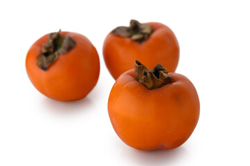 Trio of fresh persimmons on white background