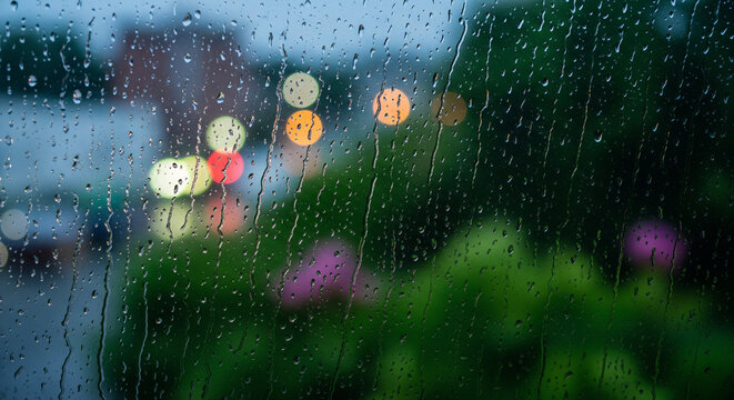 Raindrops on window glass with blurred city lights outside.
A moody and atmospheric shot of raindrops running down a windowpane, creating a texture of streaks and droplets - Powered by Adobe