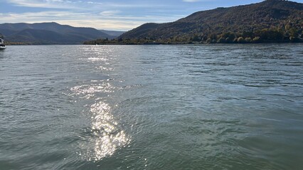 Idillic landscape of wide river Danube at sunset with sunlight reflection on water surface, autumn, forest on opposite bank.