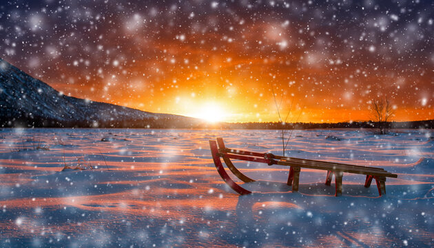 Snowy landscape with abandoned sled, snowflakes falling slowly, and an orange sunset winter sunset in the park
