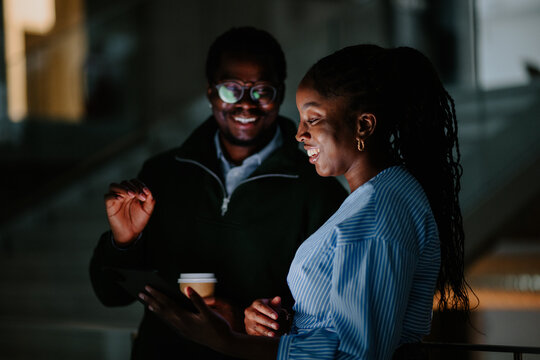 Coworkers collaborating on tablet in dark office
