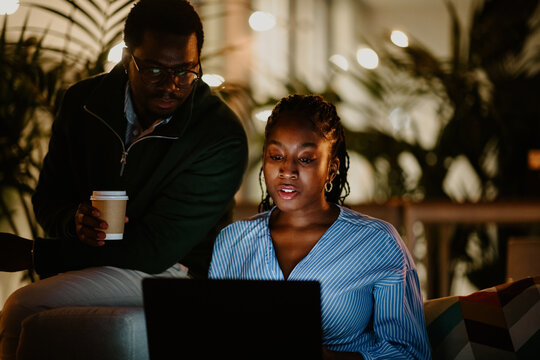 Coworkers collaborating on laptop, working late at night