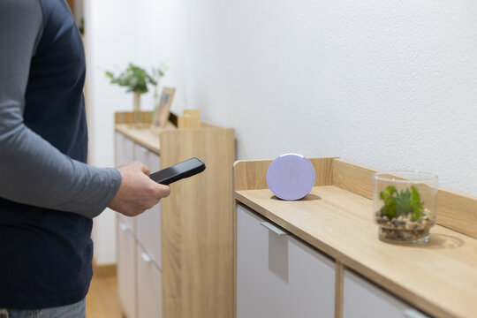 person controls smart wireless device with cell phone at home